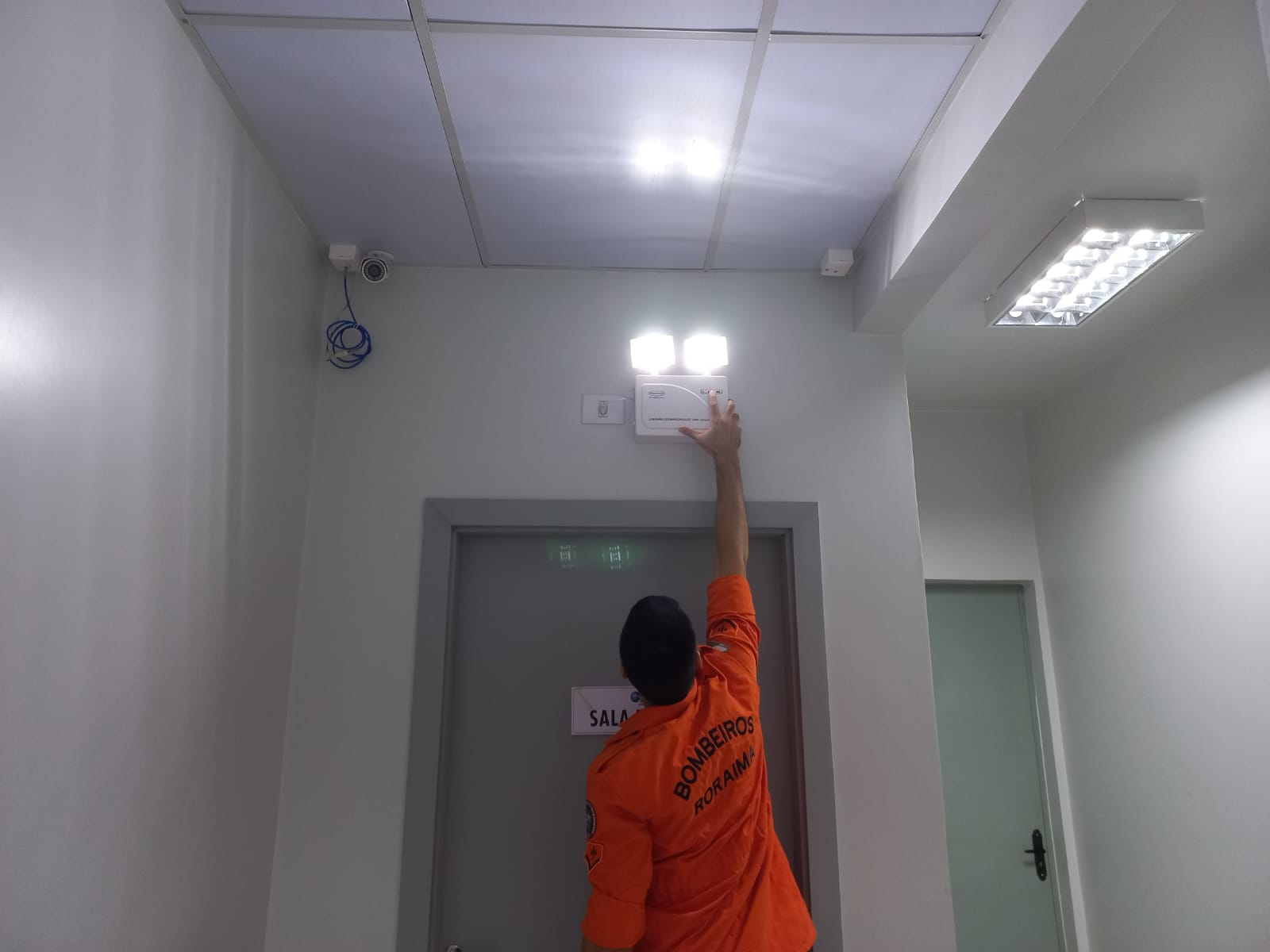 foto colorida de m bombeiro realizando a vistoria em um detector de incêndio
