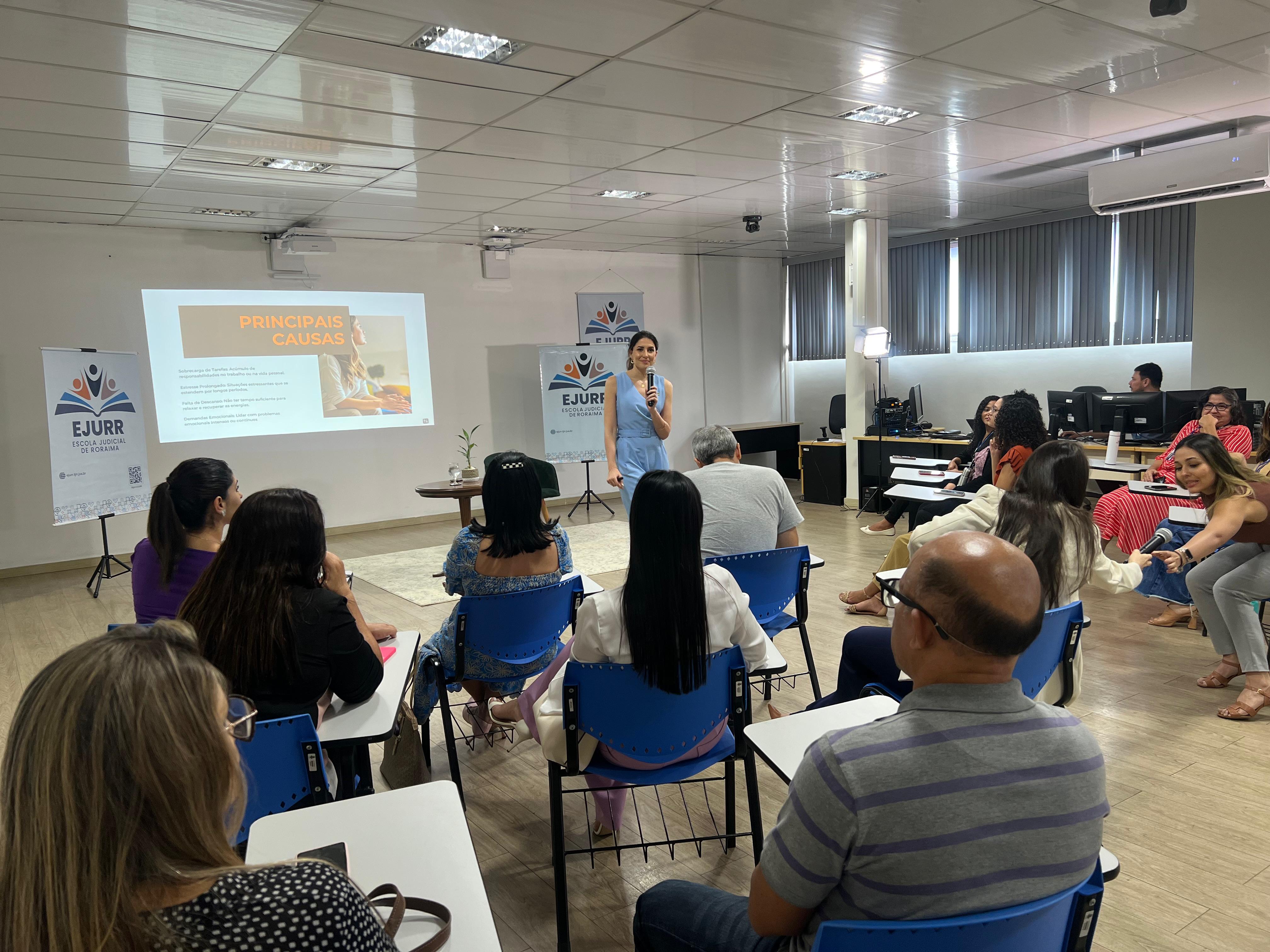 foto colorida de uma mulher dando palestra para serviras do tjrr