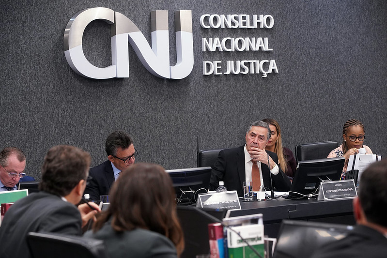 foto colorida de magistrados sentados em bancada. No fundo tem na parede fixado CNJ CONSELHO NACIONAL DE JUSTIÇA