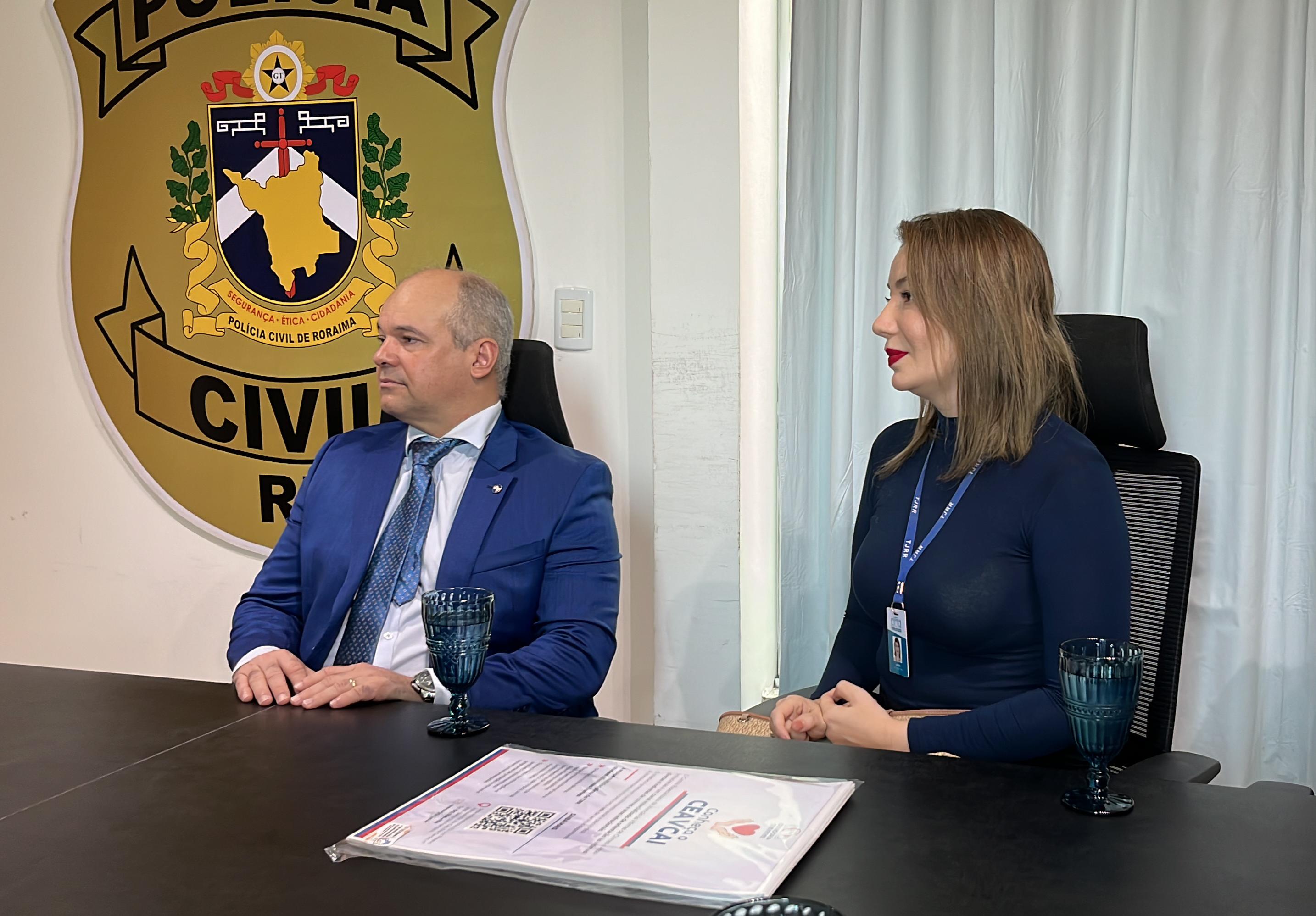 Foto colorida mostrando o juiz Eduardo Carvalho e a servidora Laura Cabral durante reunião na Polícia Civil