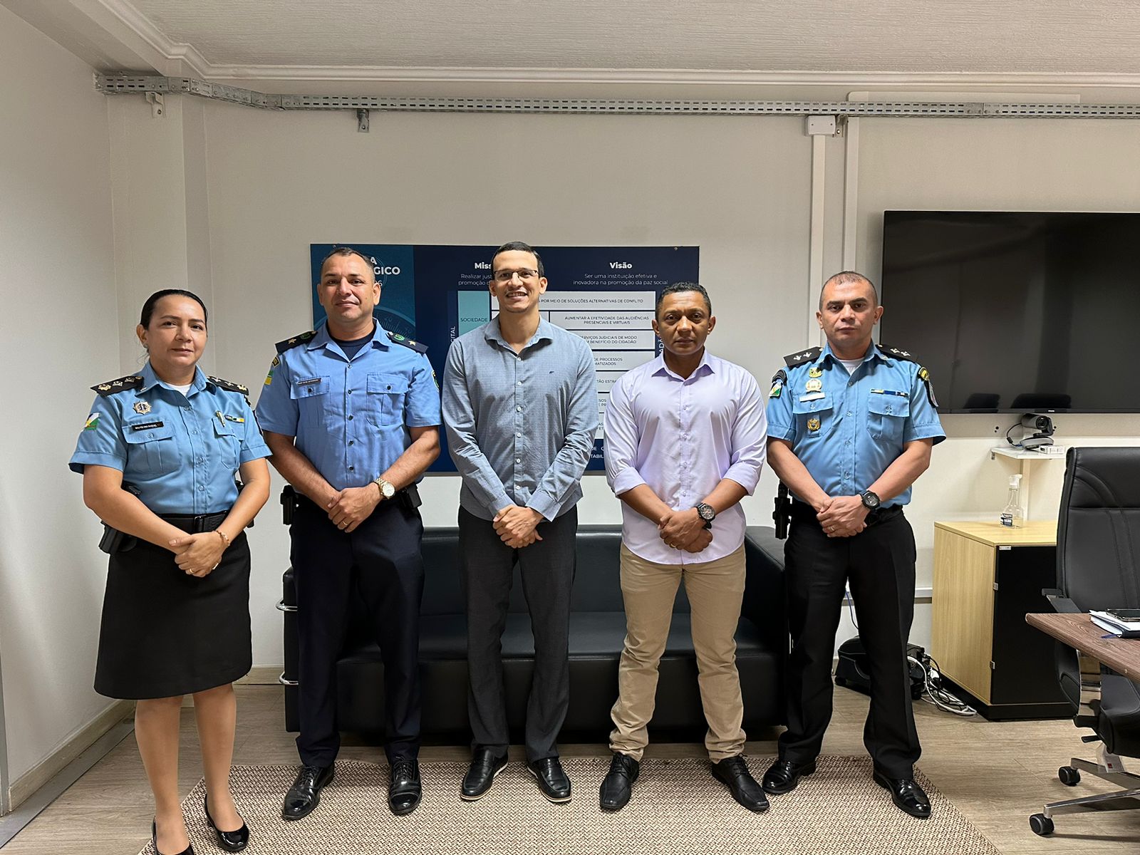 Imagem colorida mostra 5 pessoas posando para foto, que inclui Secretário-Geral do TJRR, Henrique Tavares, acompanhado pela major Ana Raquel, chefe adjunta do Gabinete Militar do TJRR, o inspetor da Guarda Civil Municipal, Jeferson de Almeida Silva, e o Secretário Municipal Adjunto de Segurança Urbana e Trânsito, Wilson Francisco da Silva