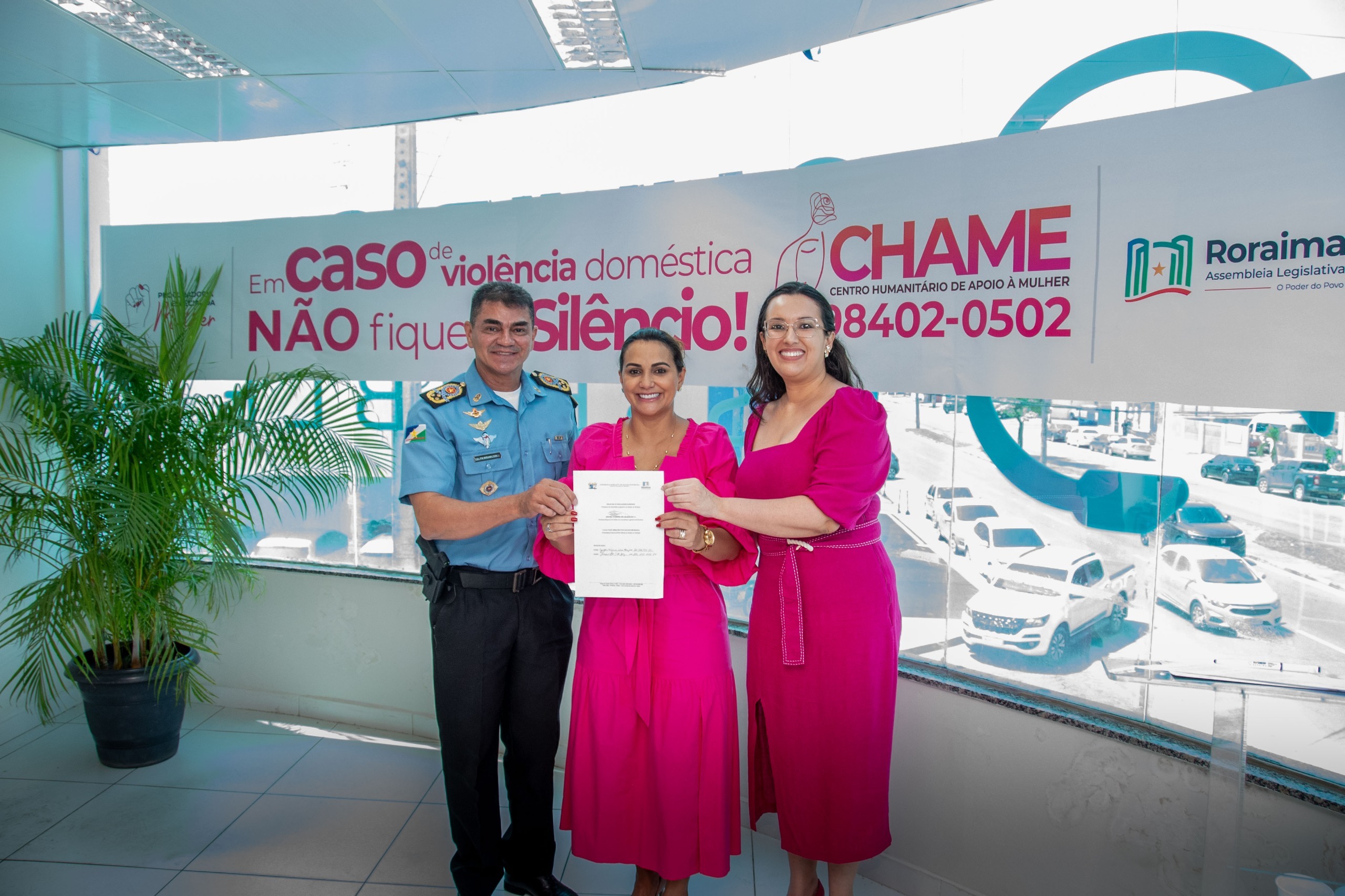 A imagem colorida mostra a juiza do 1º Juizado de Violência Domestica, Suelen Alves, ao lado do comandante-geral da PMRR, Coronel PM Miramilton Goiano, a a deputada Joilma Teodoro, durante assinatura do termo de cooperação do Tribunal de Justiça de Roraima com o Chame.