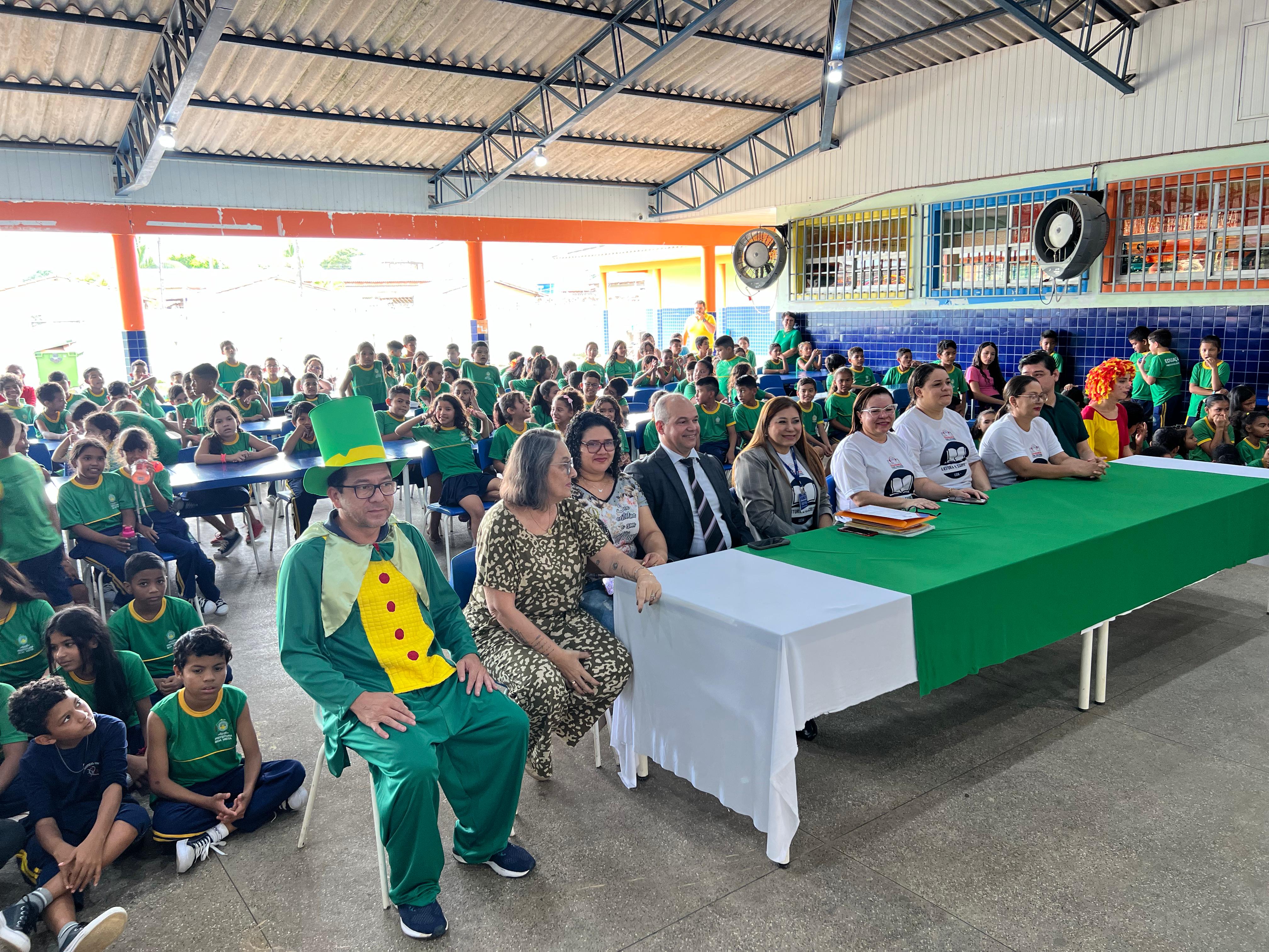 Foto colorida mostra aproximadamente 60 pessoas, entre elas alunos do ensino fundamental, profesores e autoridades do Estado