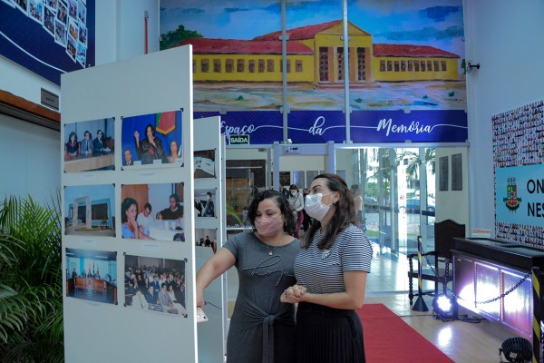 Duas mulheres de pé olhando as imagens e fotos da exposição do Espaço da Memória.