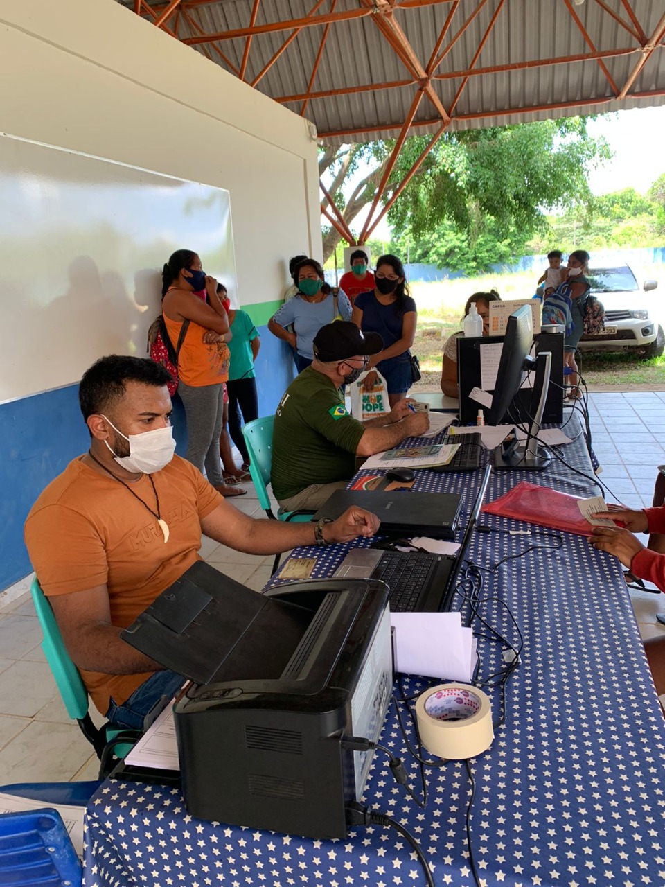 Pessoas sendo atendidas pelos servidores da Justiça Itinerante e outras pessoas aguardando atendimento.