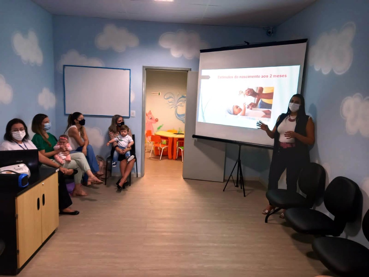 Na imagem podemos ver servidoras com seus filhos assistindo a palestra