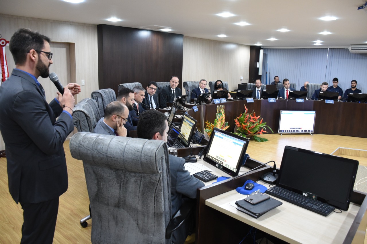 foto colorida mostra secretário de tecnologia da informação do TJRR em pé, falando ao microfone ao lado esquerdo de onde  estão sentados os magistrados na tribuna.