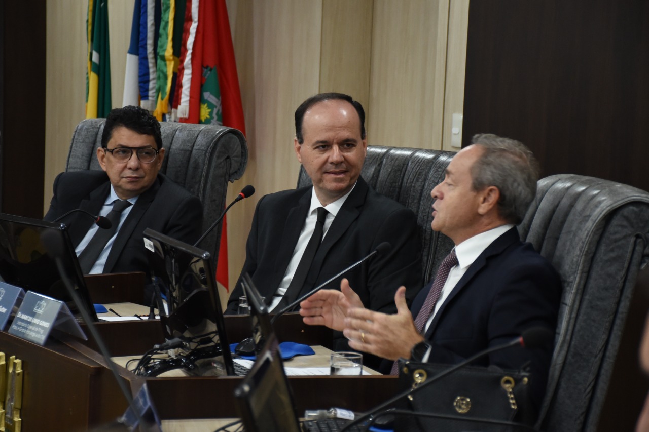 foto colorida mostra três pessoas sentadas. Ao lado esquerdo o vice-presidente do TJRR e ao centro o presidente do TJRR, ambos observam a fala do secretário especial de programas, pesquisas e gestão estratégica do CNJ, que está ao lado direito falando ao microfone.