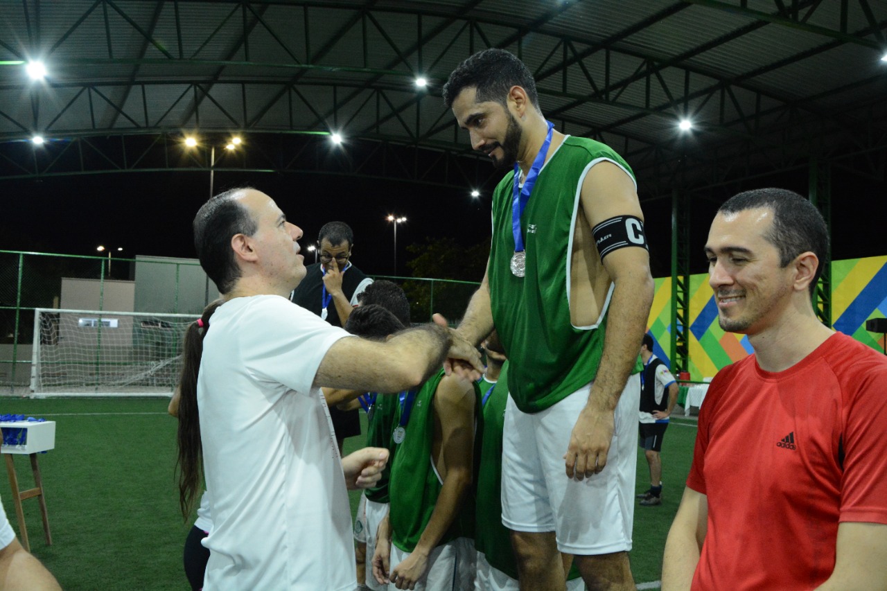  Imagem colorida contém o presidente do TJRR, desembargador Cristôvão Súter,  entregando medalha para participante do  I FutJus.