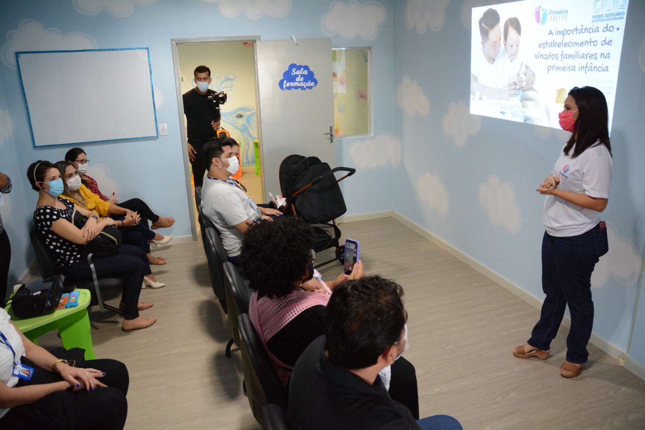 Foto mostra pessoas em uma sala assistindo a uma palestra dos programa Primeiros Passos. 