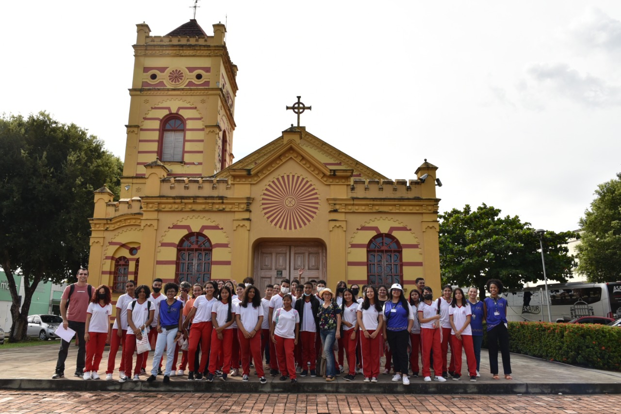 Imagem colorida contém alunos da Escola Estadual Oswaldo Cruz, em frente à Igreja Matriz Nossa Senhora do Carmo , durante excursão em prédios históricos da Capital do Estado de Roraima.