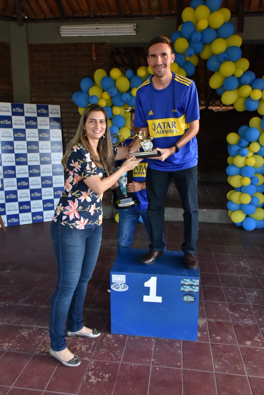 Imagem colorida contém servidora do TJRR, Ivy Marques Amaro entregando prêmio para o estagiário Juliano Santos.