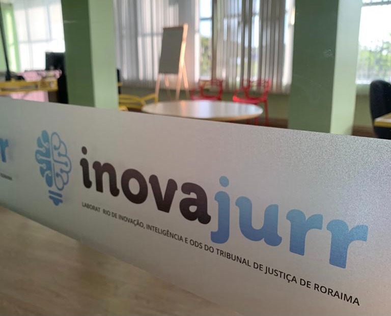 Imagem colorida da faixa adesivada na porta de vidro do Laboratório de Inovação, Inteligência e ODS do Tribunal de Justiça de Roraima. 