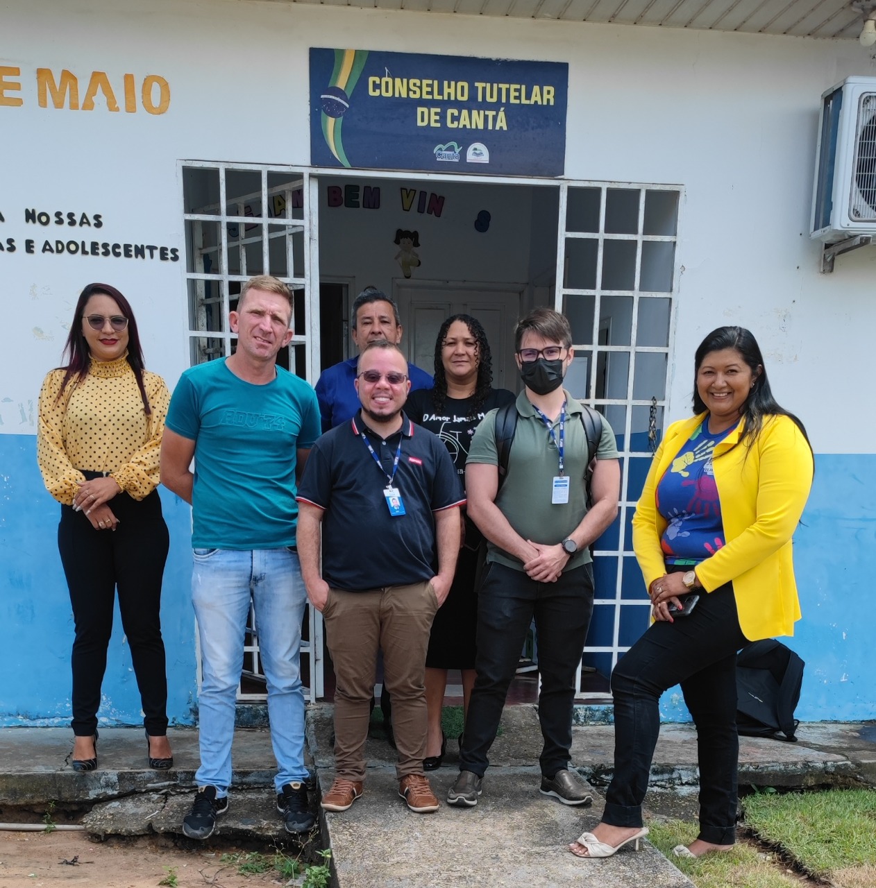 Imagem colorida com 7 pessoas em pé na entrada do conselho tutelar de cantá