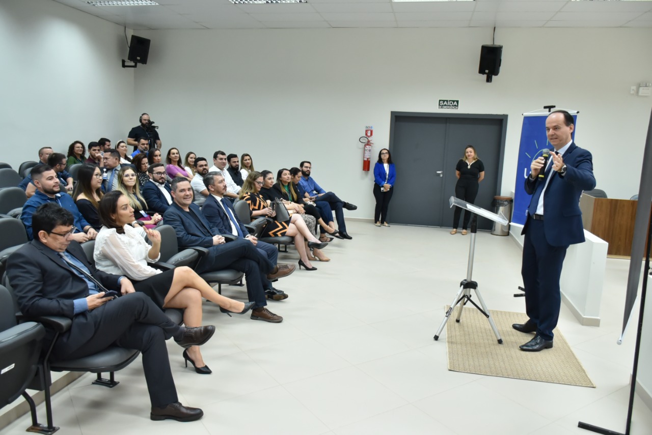 Imagem colorida mostra o  presidente TJRR, desembargador Cristóvão Suter discursando em um auditório, para um pequeno público de homens e mulheres.