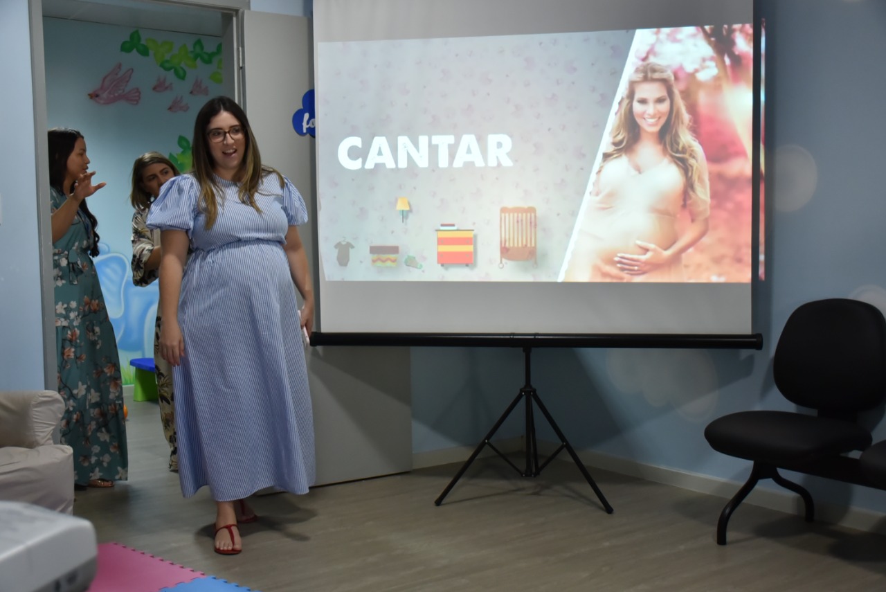 Imagem colorida contém três mulheres entrando pela porta da sala do Programa Primeiros Passos. 