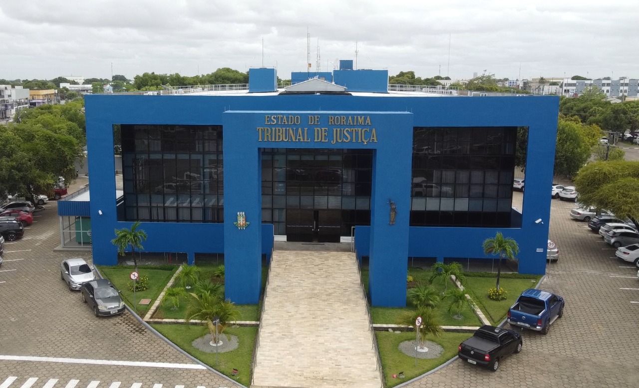 Imagem aérea, colorida e em formato retangular mostra a fachada do Palácio de Justiça do Estado de Roraima, nas laterais do prédio, há árvores e veículos estacionados.