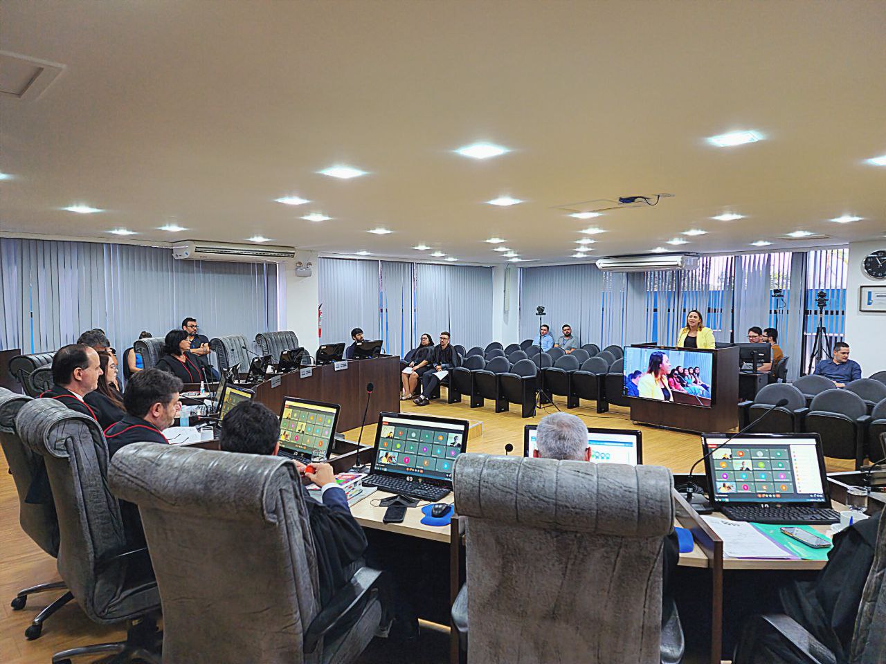 Imagem colorida mostra o presidente, Cristóvão Suter em uma sessão no pleno. Na sala há uma bancada em forma posicionada à frente de um pequeno auditório, sobre a bancada estão onze computadores exibindo uma sala de reunião virtual. Na imagem aparecem 20 pessoas, sendo estes magistrados e magistradas, servidores e servidoras do Tribunal de Justiça.