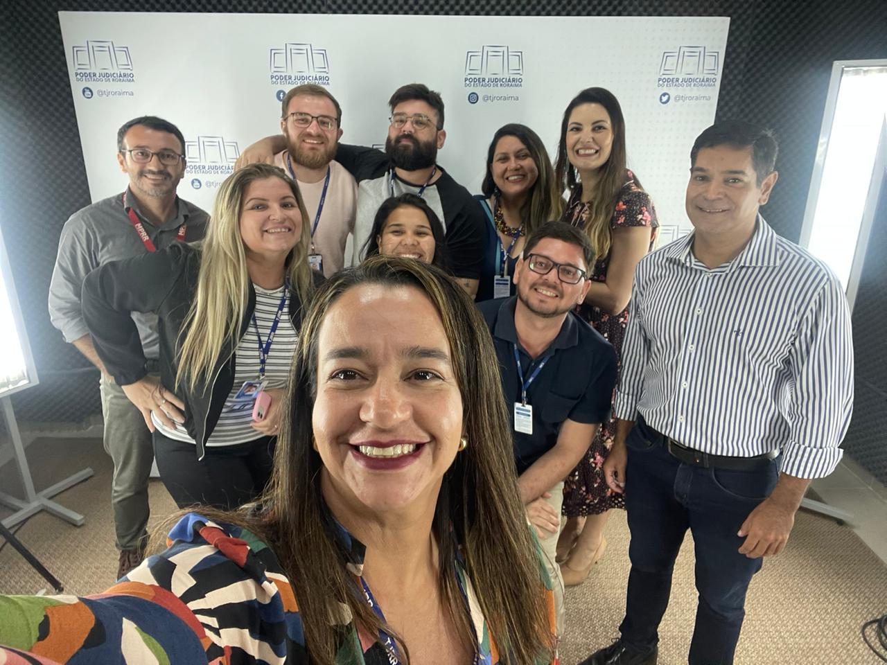 Imagem colorida em formato retangular mostra a coordenadora do NUCRI, Débora Morais, e a chefe do Escritório de Jornalismo do Núcleo de Relações Institucionais (Nucri/TJRR), Tarsira Rodrigues, com os jornalistas Yano Sérgio, coordenador de Comunicação Social do MPRR, Aline Jimenez, assessora técnica de comunicação, e Ricardo Rodrigues, assessor técnico de comunicação e a equipe do Nucleo de comunicação do TJRR, Mairon, Adriã, Ericka, Lucas e Marcelo, durante uma selfie.