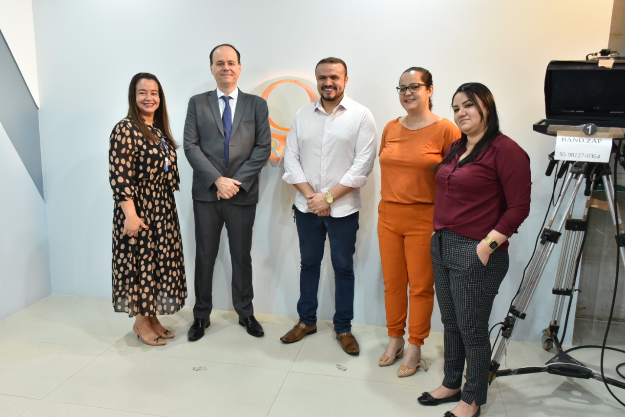 Imagem colorida em formato retangular mostra o presidente do Tribunal de Justiça de Roraima, desembargador Cristóvão Suter, a coordenadora do NUCRI, Débora Morais e a equipe da Tv Record composta por duas mulheres e um homem.