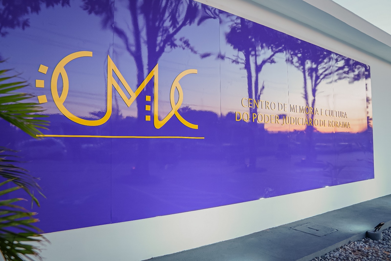 Imagem colorida em formato retangular mostra um painel na cor roxa com o logotipo “CMC” e ao lado a frase “Centro de Memória e Cultura do Poder Judiciário", ambas escritas na tonalidade amarela.