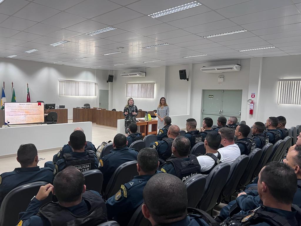 Imagem colorida mostra um auditório lotado de policiais militares fardados. A frente em pé a juíza titular da comarca, Rafaella Holanda e a juíza titular da Coordenadoria Estadual da Mulher em Situação de Violência Doméstica e Familiar do TJRR, Suellen Alves.