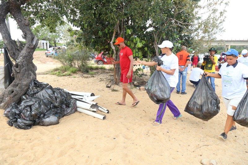 foto coloria de servidores do TJRR arrecadando lixo na praia