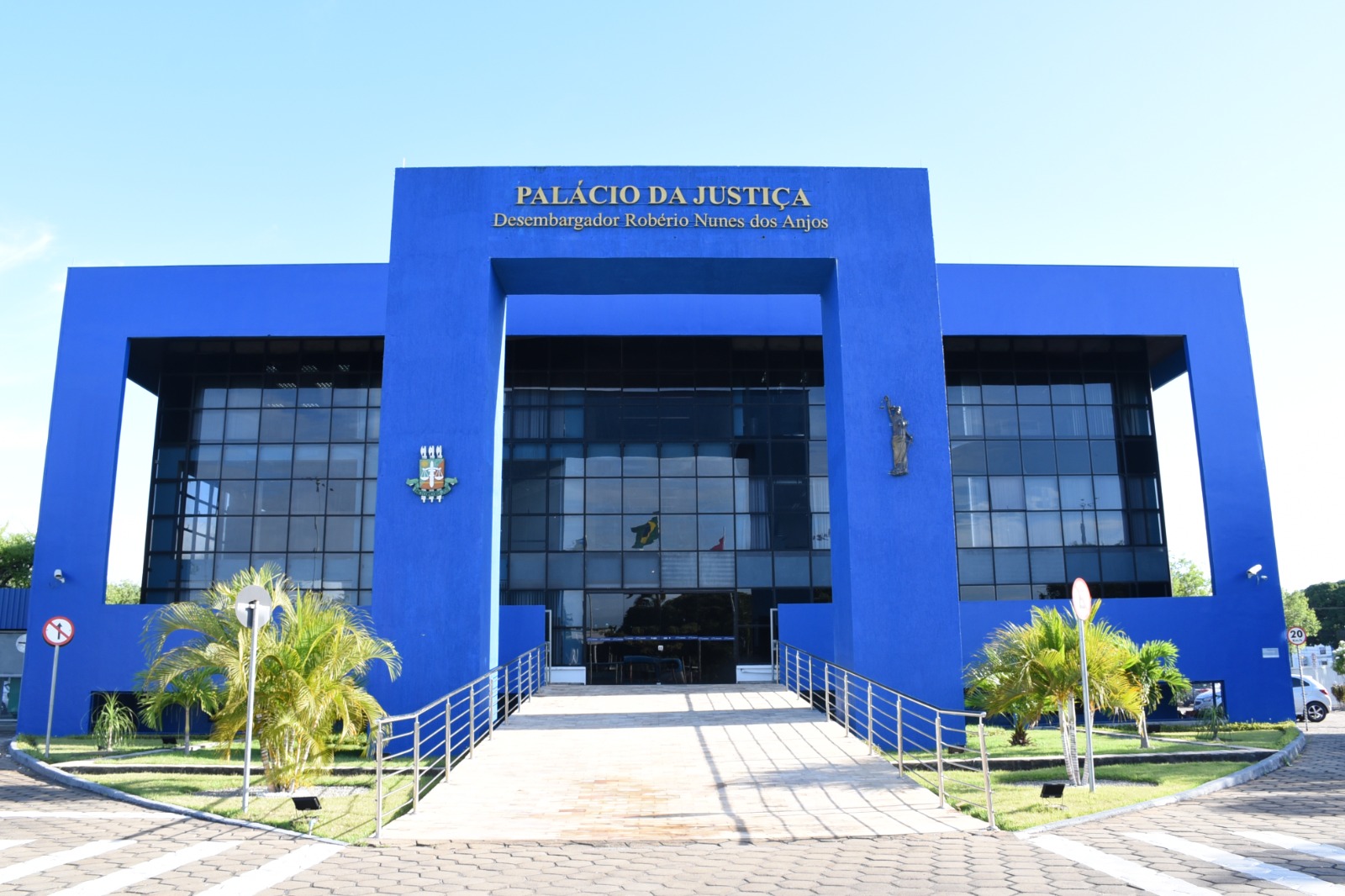 Imagem colorida mostra a fachada do prédio do Palácio da Justiça, o edifício pintado na cor azul escuro está identificado com o nome “ Estado de Roraima, Tribunal de Justiça” pintado de dourado.