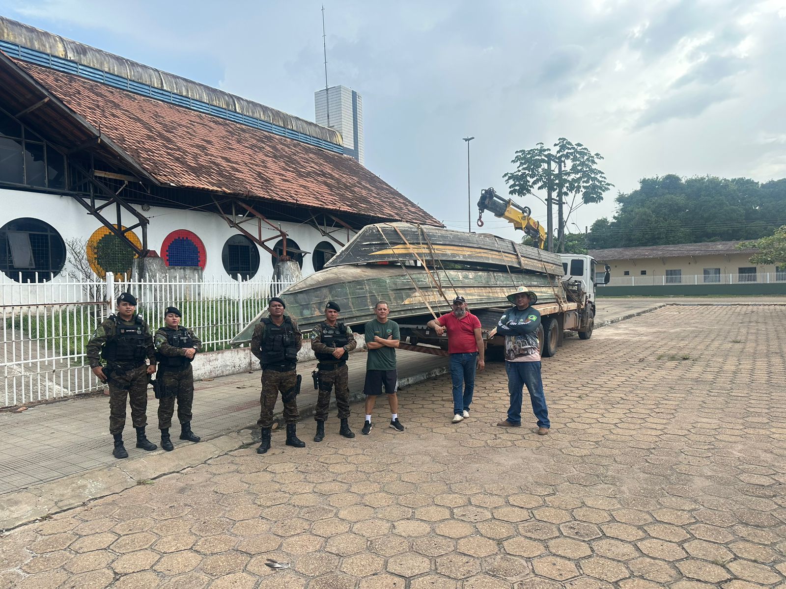 foto colorida na frente do predio Latine Salomão com policiais pousando para foto com dois barcos atraz