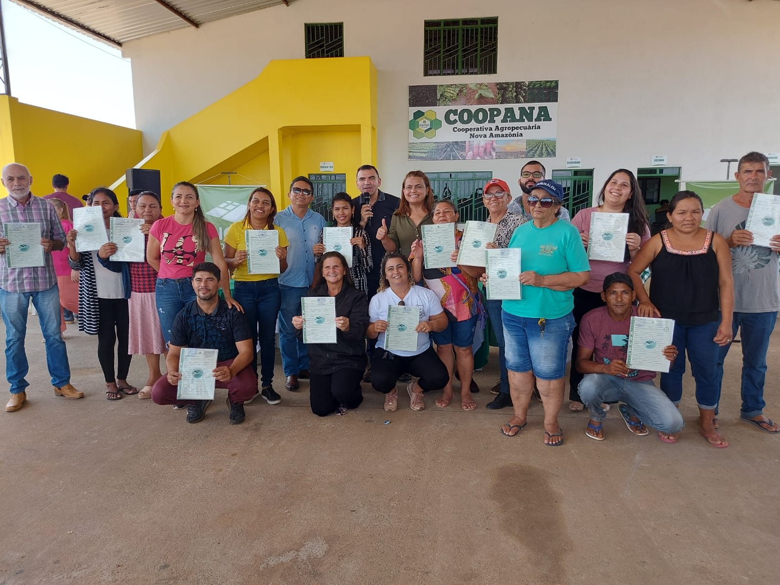 foto colorida de beneficiários pousando para a foto e com os titulos na mão