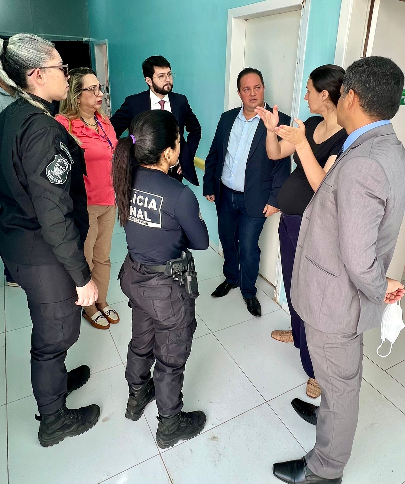 foto colorida com o juiz Daniel Damasceno Amorim Douglas juntamebte com os inegrantes do sistema penal em um corredor da parte interna do local