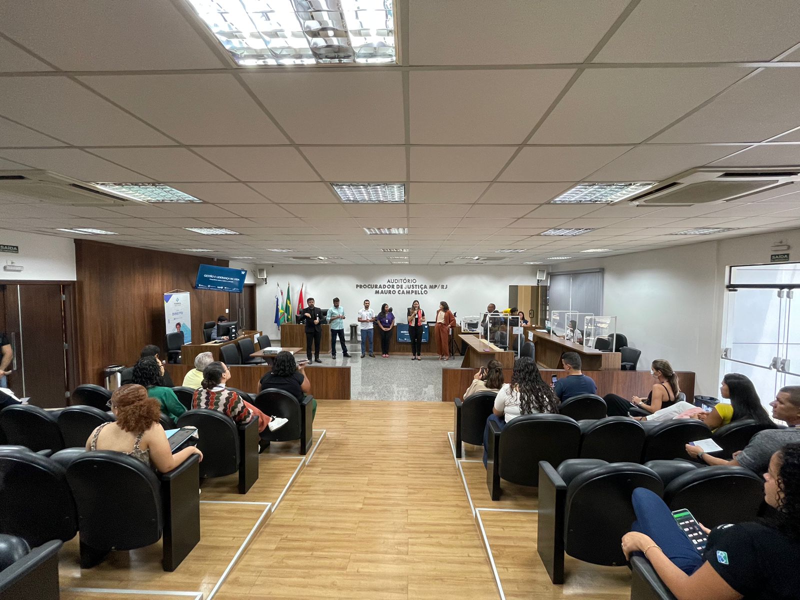 foto colorida mostra pessoas reunidas no Auditório Procurador de Justiça MP/RJ Mauro Campello, do Fórum Criminal Ministro Evandro Lins e Silva do TJRR, enquanto o Secretário de Comunicação do Estado de Roraima, Weber Negreiros, ministra palestra e o tradutor de libras ao lado, durante “Ação Cuidando do Servidor”.