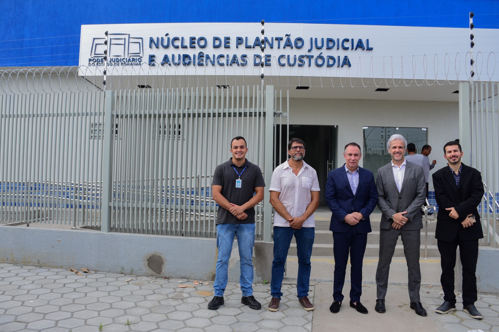 Cinco homens posicionados em frente ao Núcleo de Plantão Judicial e Audiências de Custódia (Nupac)