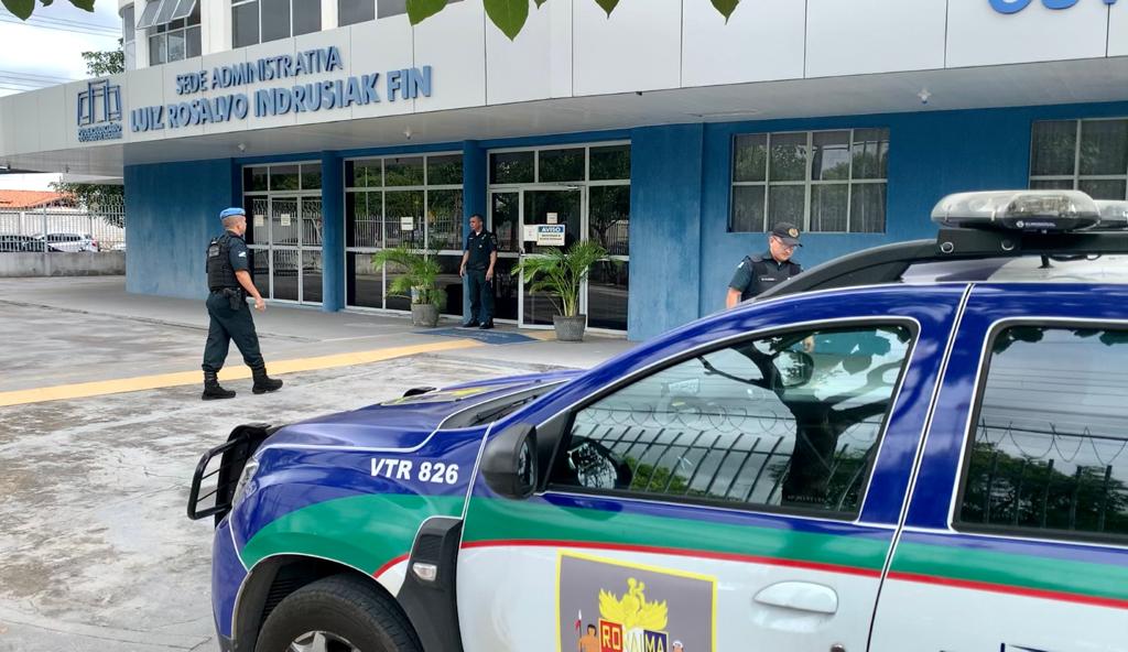 foto colorida da frente do prédio administrativo do TJRR, a frente contém a viatura da Polícia Militar e há policiais andando pela calçada