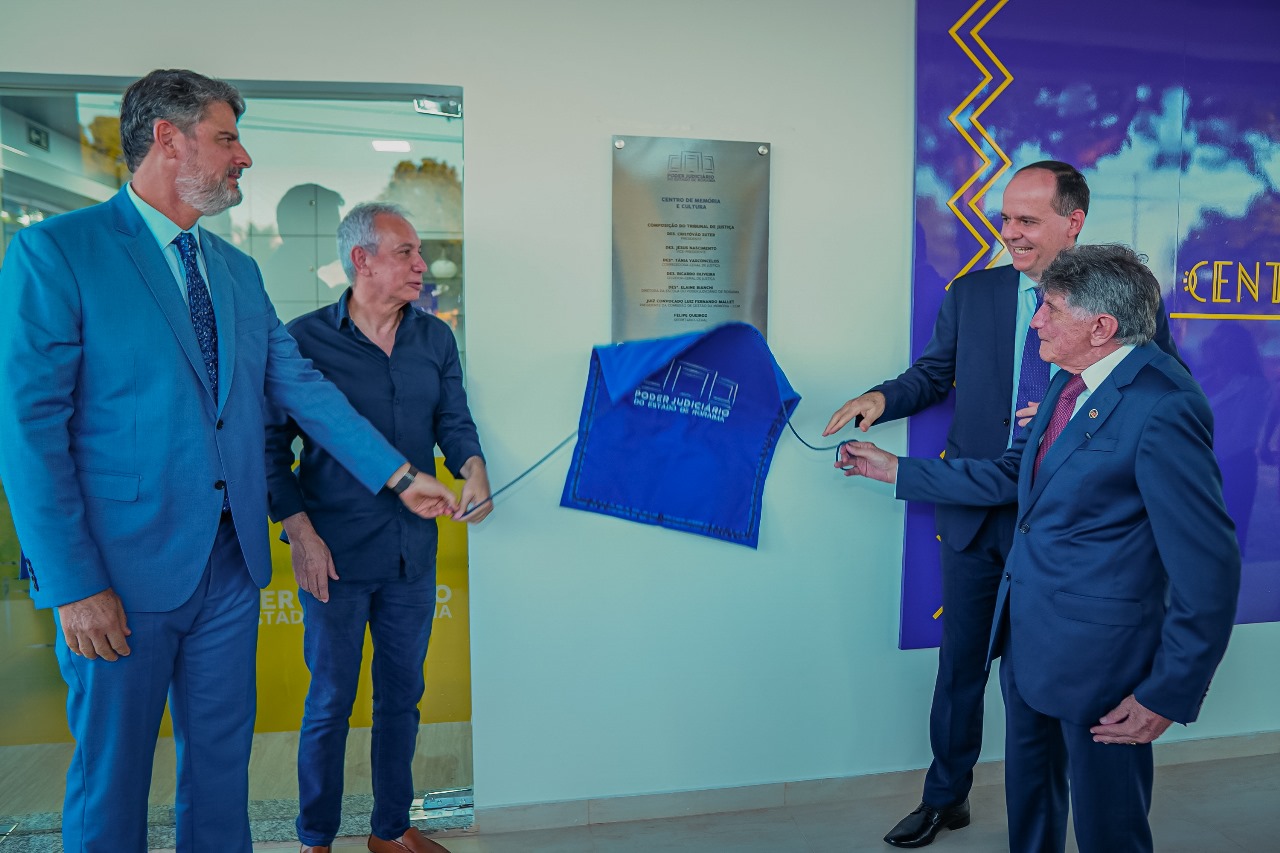 Foto colorida mostrando os desembargadores Almiro Padilha e Cristóvão Suter, juntamente com o juiz convocado Luiz Fernando Mallet, descerrando a placa de inauguração do Centro de Memória.