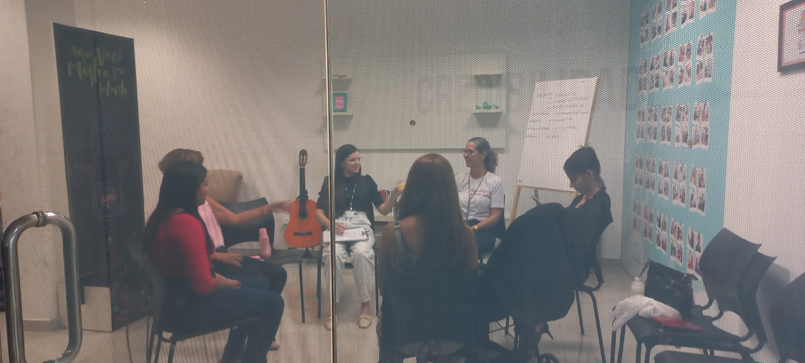 Foto colorida mostra cinco pessoas dentro de uma sala durante uma roda de conversas.