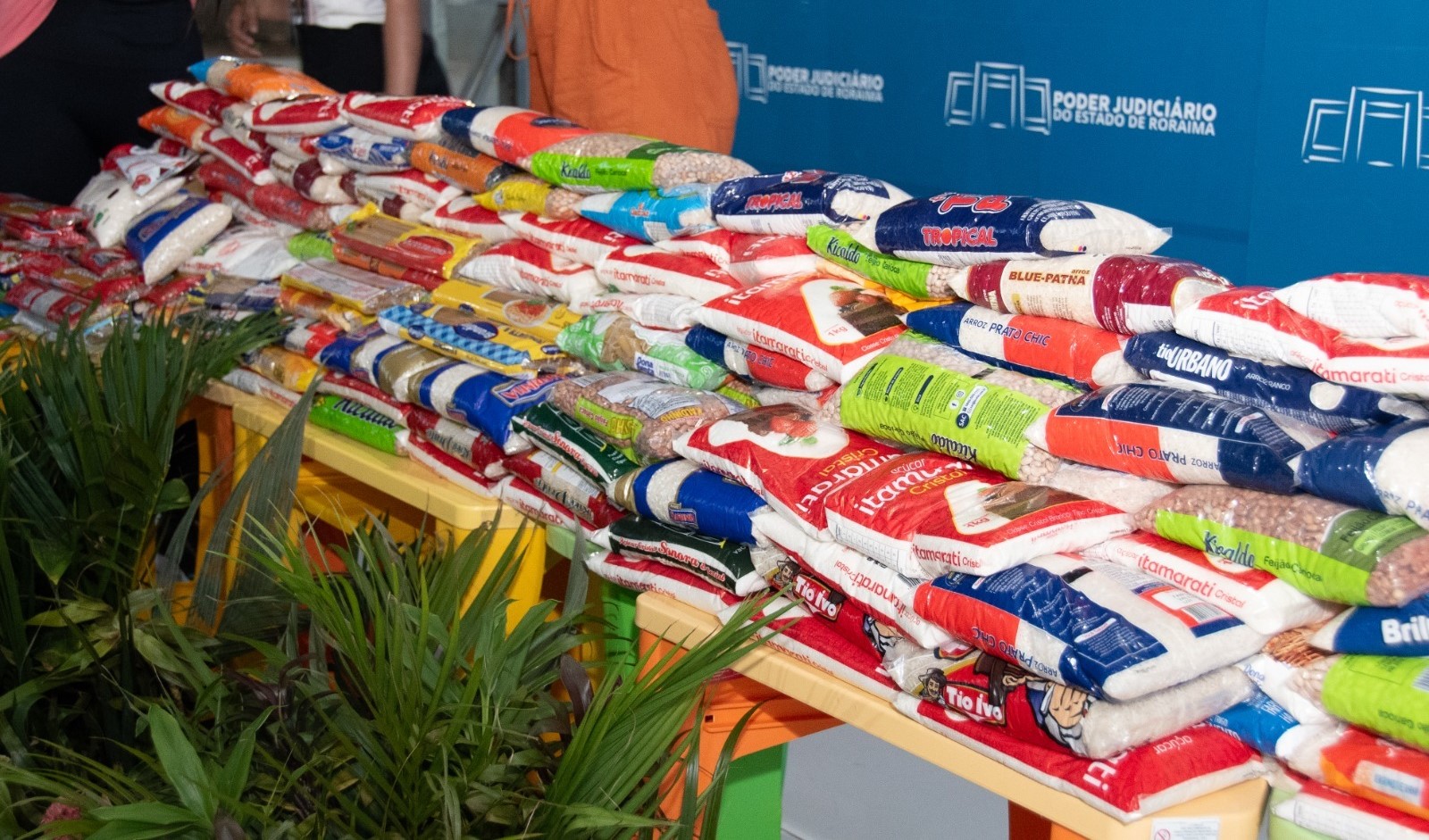 Imagem colorida mostrando alimentos empacotados empilhados em cima de uma mesa