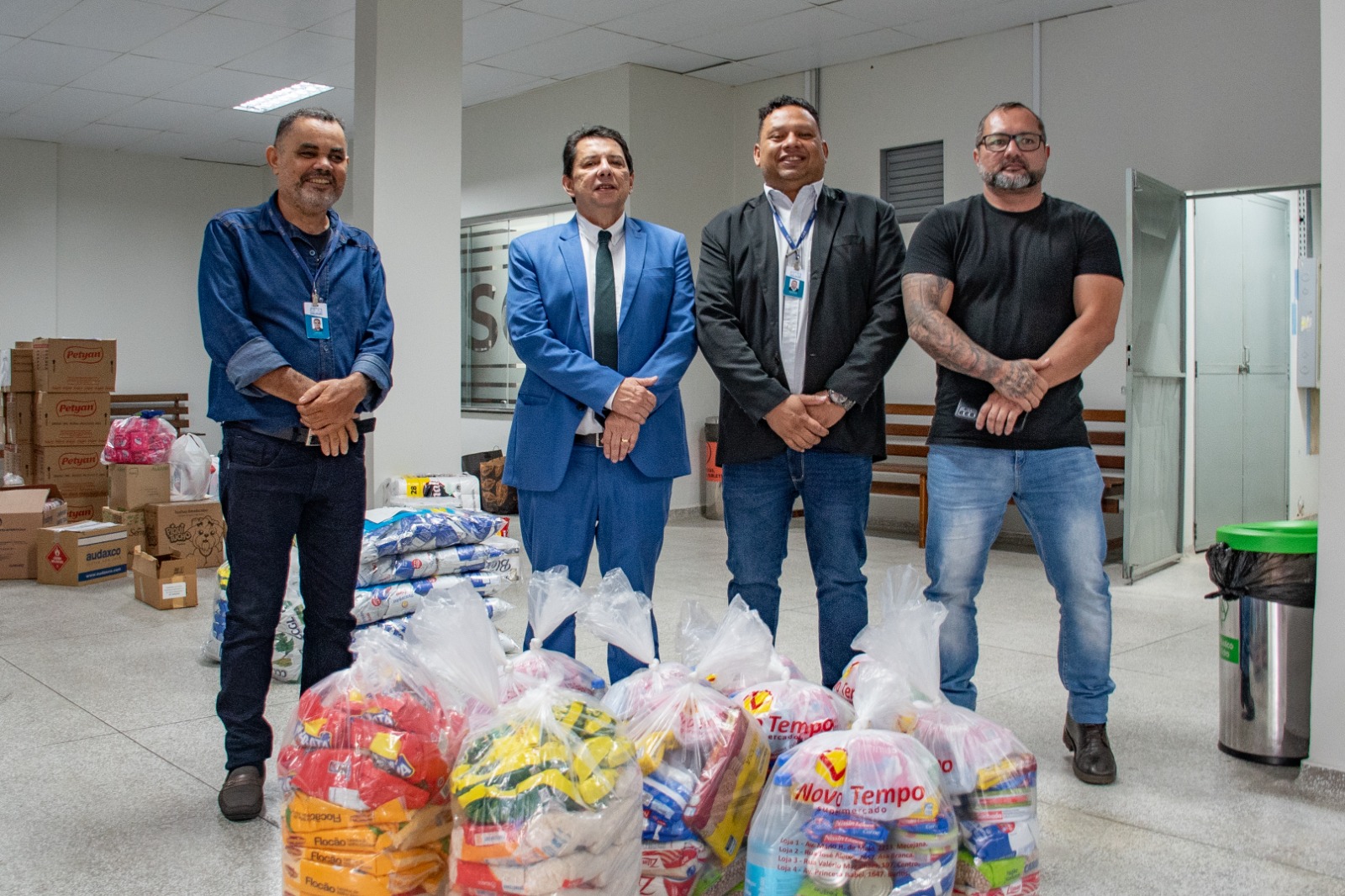 Foto colorida mostrando o o presidente do Tribunal de Justiça de Roraima, desembargador Jésus Nascimento, ao lado de 3 servidores do TJRR, posando para foto. Em frente a eles cestas basicas