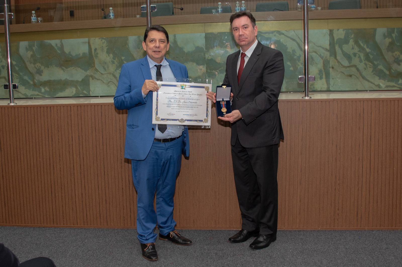 Imagem colorida do presidente do Tribunal de Justiça de Roraima, desembargador Jésus Nascimento, recebendo o diploma e a medalha do procurador-geral, Jean Pierre Michetti.