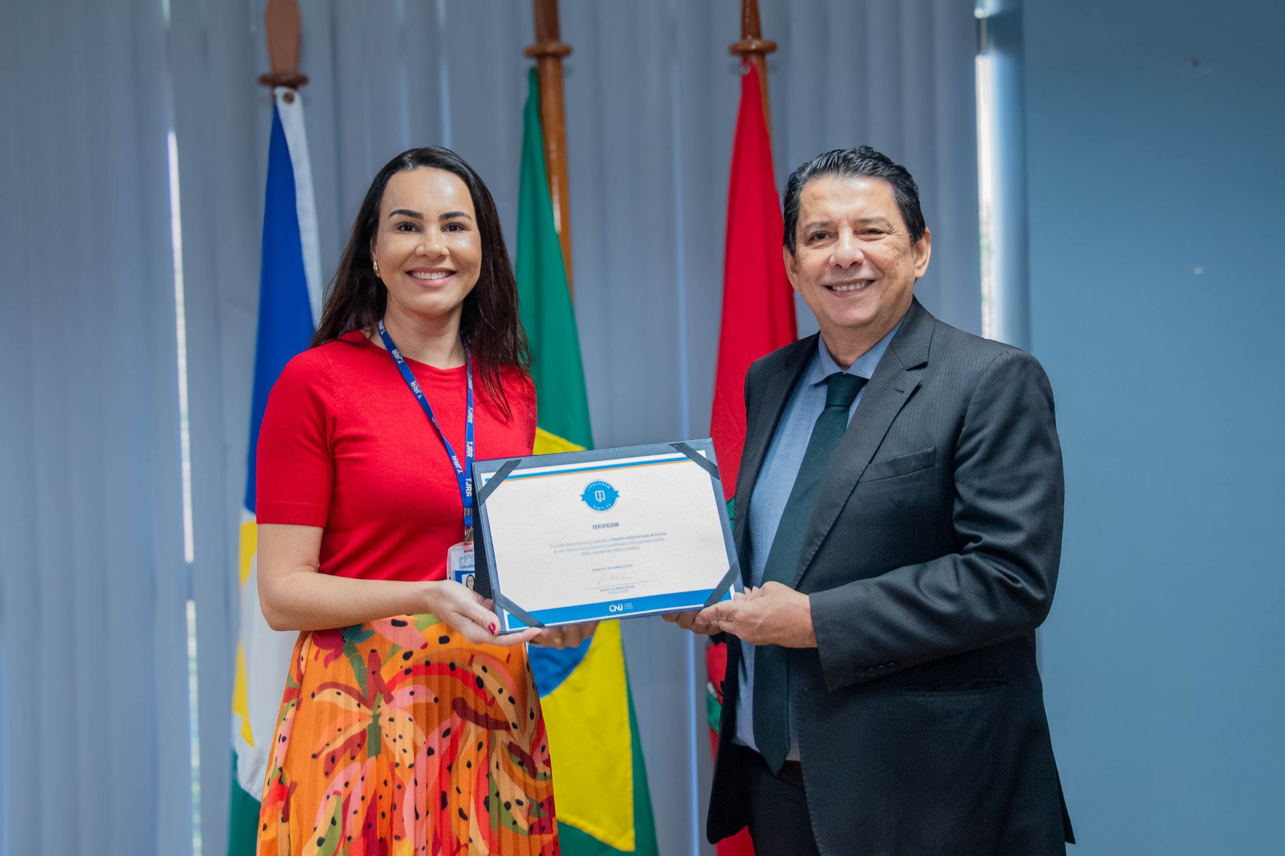 TJRR é reconhecido com Selo de Linguagem Simples pelo CNJ - Foto colorida mostra o presidente do TJRR e a chefe do NPI segurando o certificado de linguagem simples.