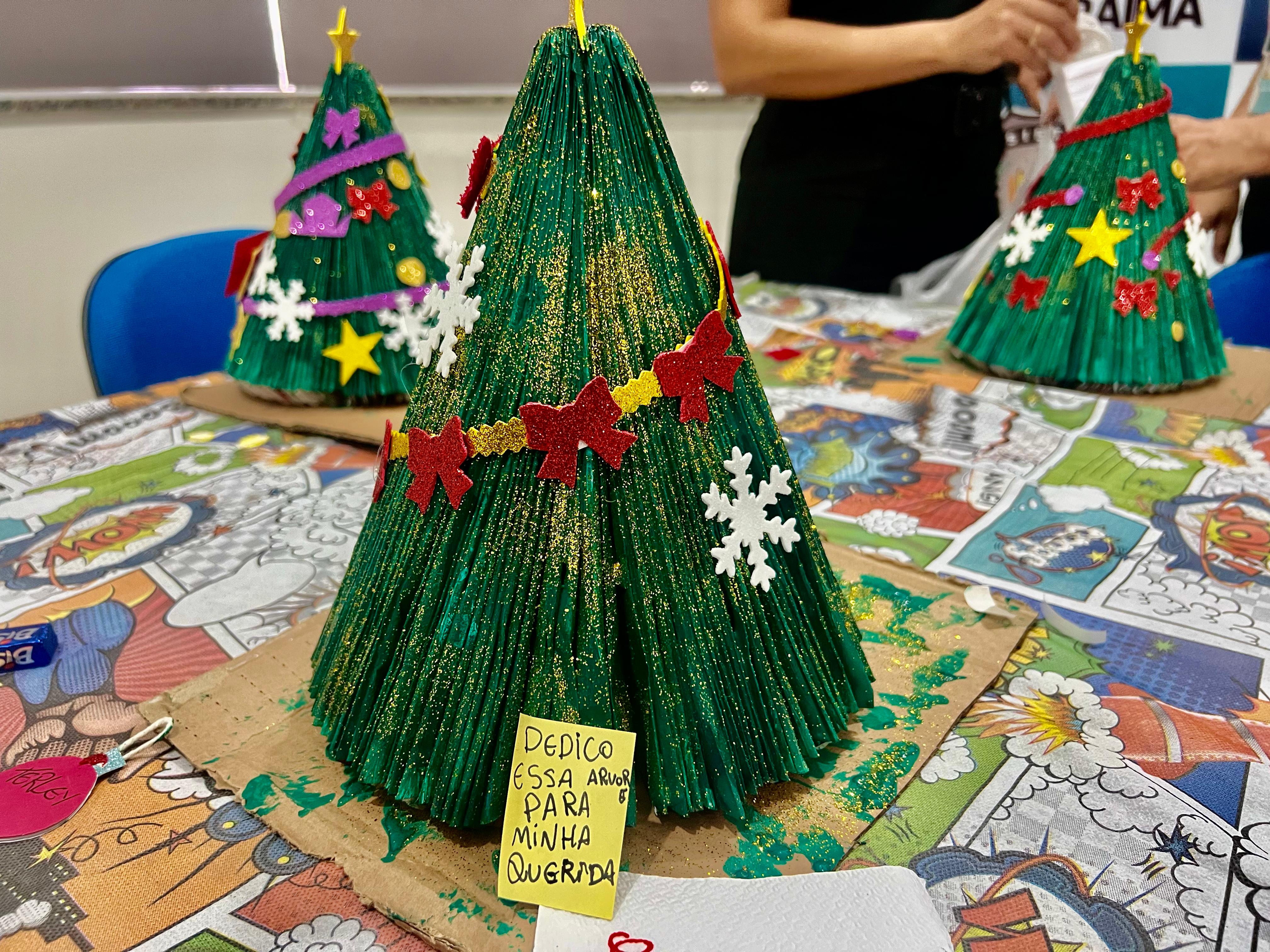 foto colorida mostra três mini árvores de natal sendo confeccionadas