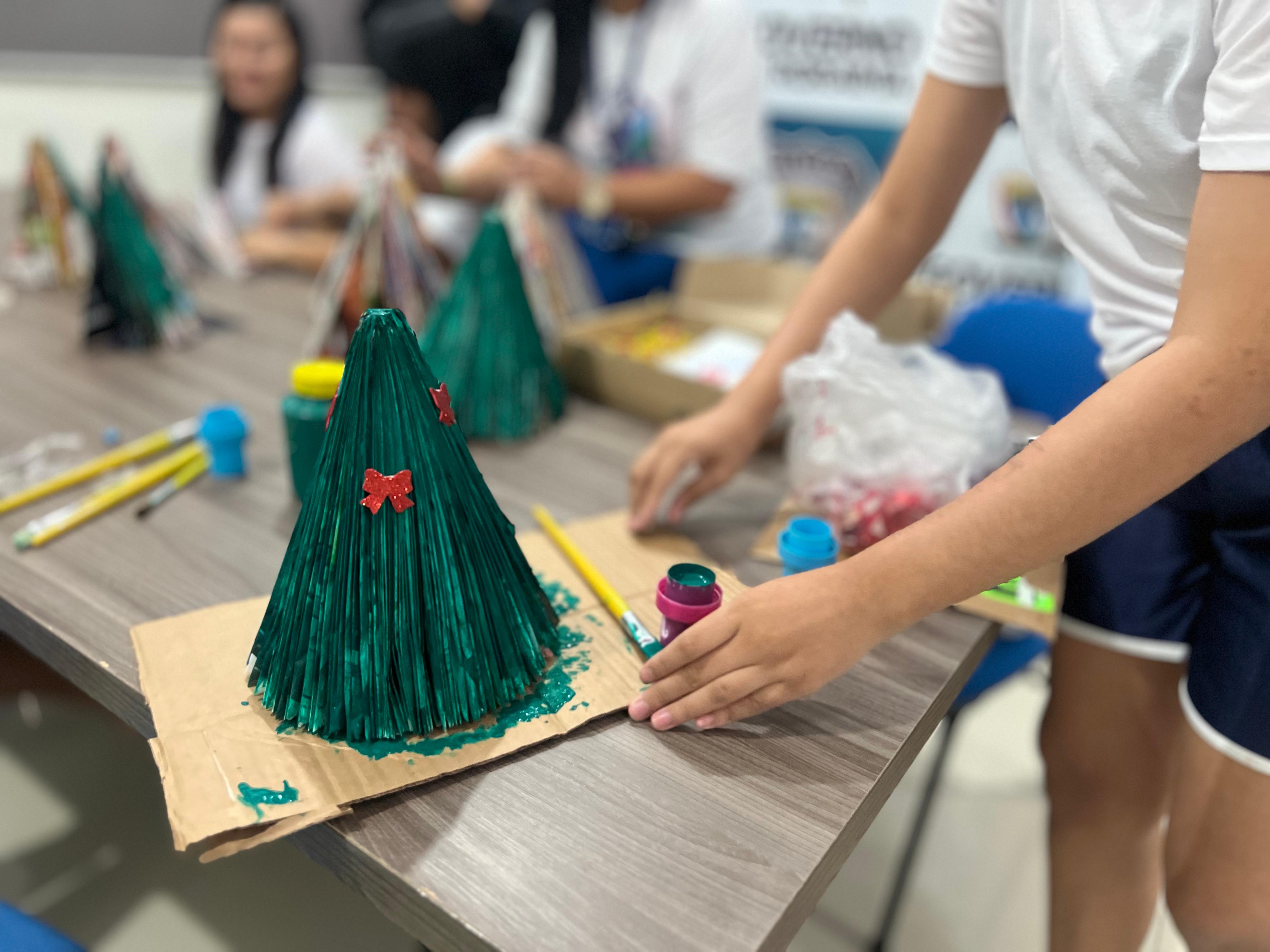 foto colorida mostra uma mini árvore de natal sendo confeccionada