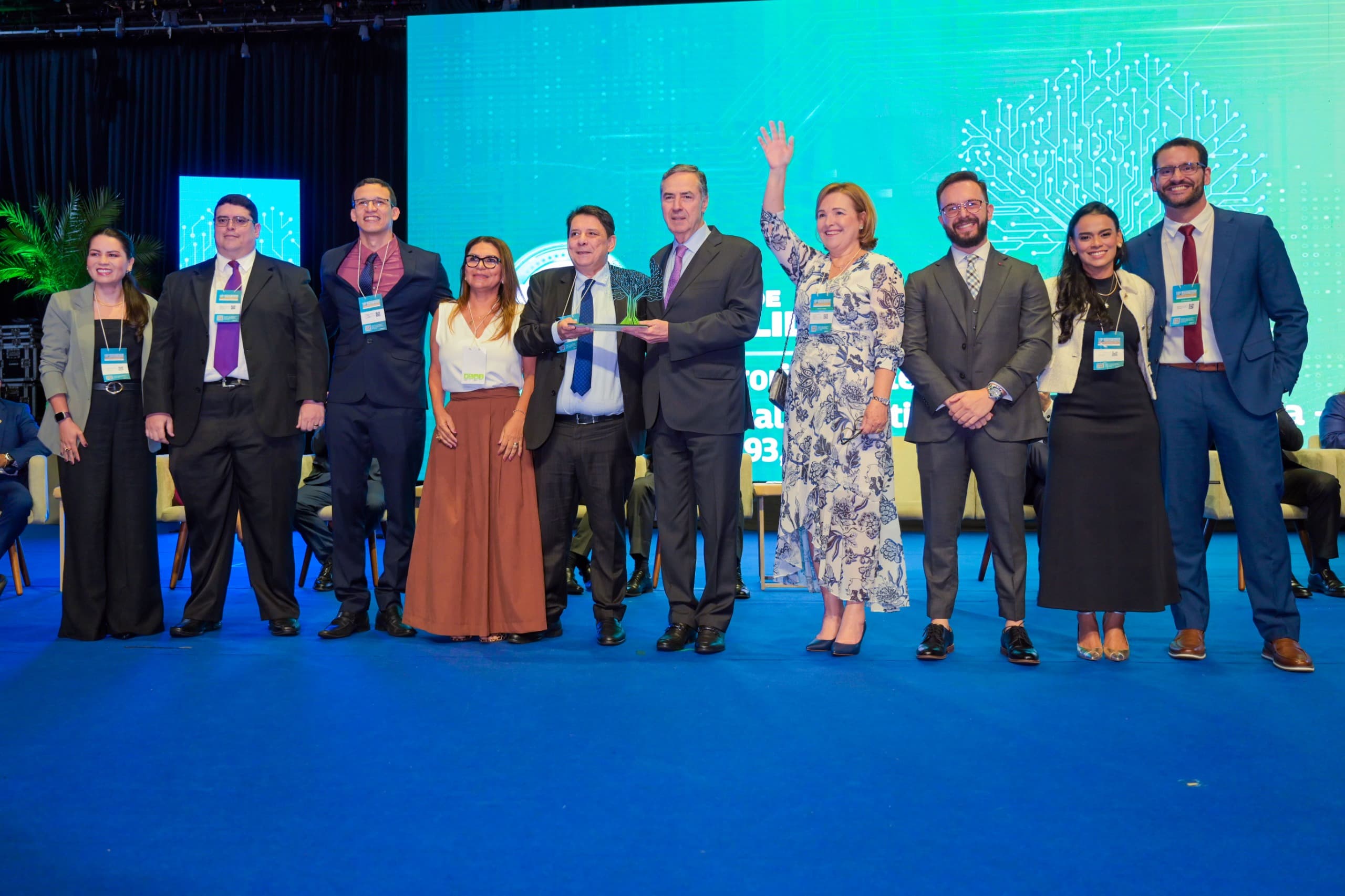  Foto colorida tirada durante a premiação do Selo CNJ de Qualidade. Na foto, no centro da imagem, o presidente do TJRR, desembargador Jésus Nascimento, segura o Selo Excelência, juntamente com o ministro  Luís Roberto Barroso. Ao lado deles, a presidente do Tribunal Regional Eleitoral, Elaine Bianchi, o juiz auxiliar da presidência do TJRR, Esdras Benchimol, a juíza titular da Vara da Justiça Itinerante, Graciete Sotto Mayor, o secretário Geral, Henrique Tavares, a secretária de Gestão Estratégica , Veruska Lobo,a secretária de Gestão de Magistrados, Fernanda Cantanhede,  o secretário de Tecnologia da Informação , Tiago Lobo, e o coordenador da Assessoria Jurídica da presidência, Alexandre Martins.