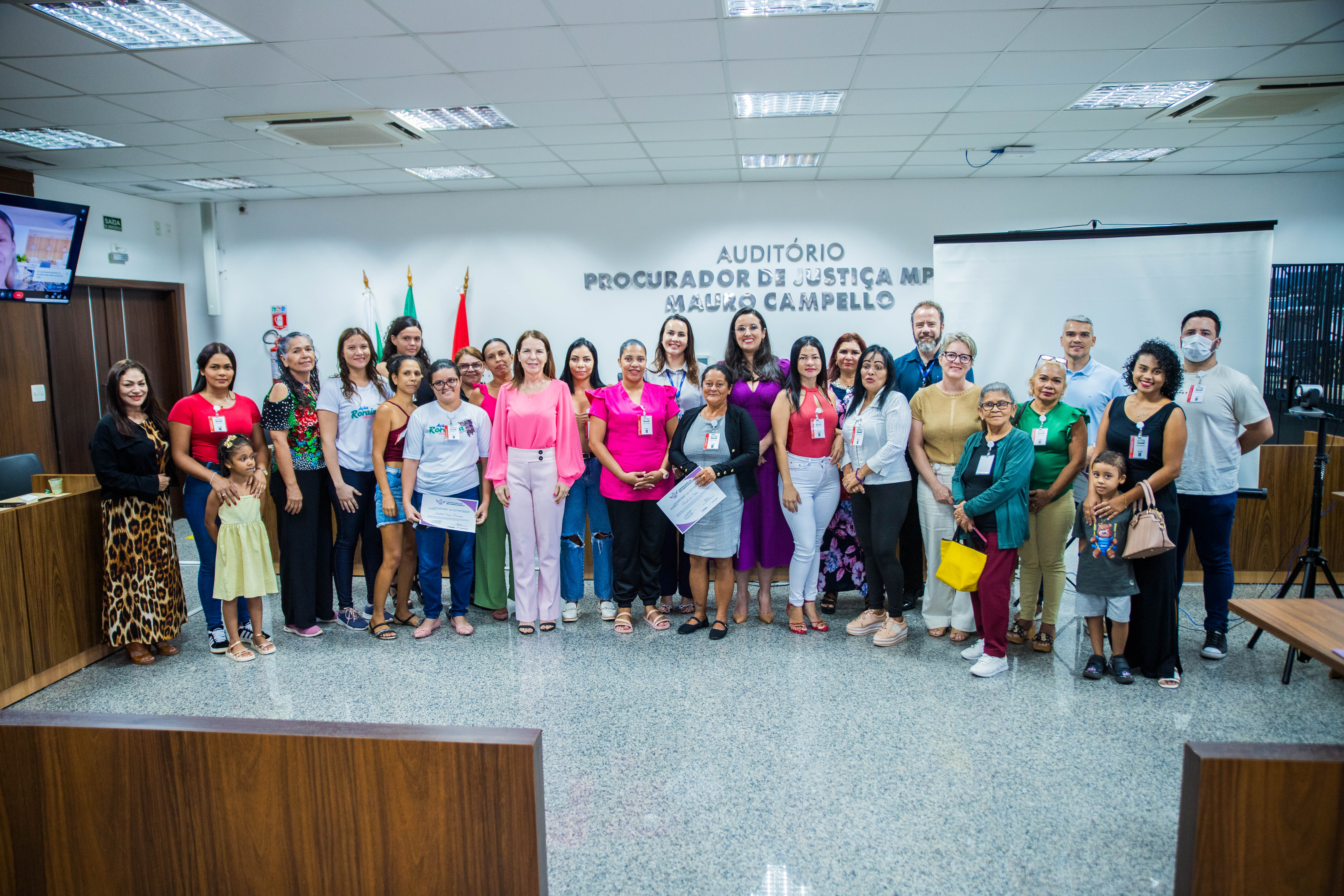 Foto colorida mostra um grupo com participantes do Projeto Investidor Anjo, realizado pelo Tribunal de Justiça de Roraima. Mulheres e apoiadores estão reunidos em um auditório durante a entrega de certificados.