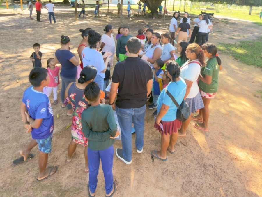 Moradores, incluindo crianças e adultos, recebem orientações da equipe da Justiça Itinerante em área aberta de comunidade rural. Moradores, incluindo crianças e adultos, recebem orientações da equipe da Justiça Itinerante em área aberta de comunidade rural.