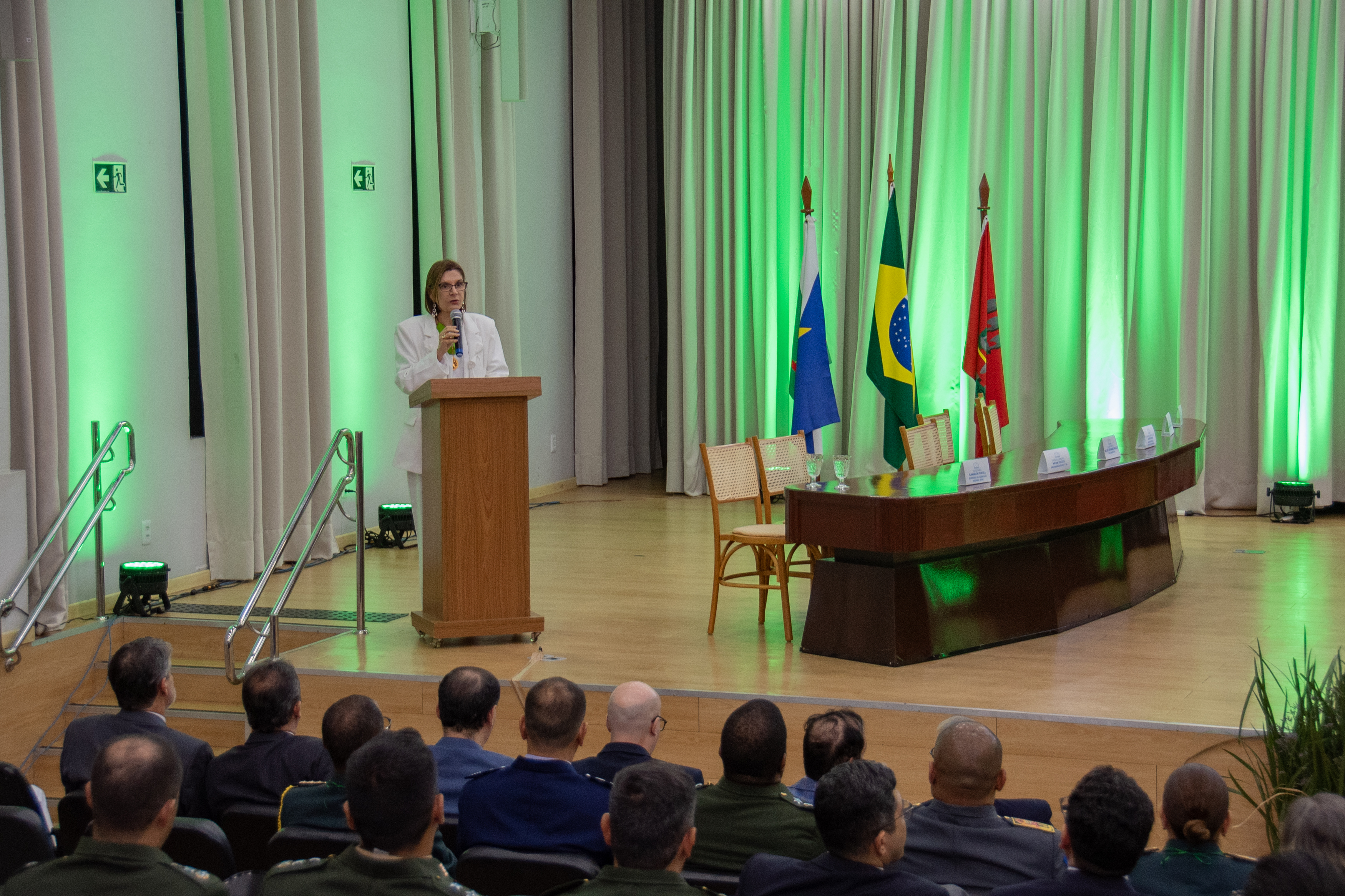 Imagem colorida registra a presidente do Superior Tribunal Militar (STM), ministra Maria Elizabeth Guimarães Teixeira Rocha, falando ao microfone no púlpito durante a solenidade comemorativa dos 24 anos da Justiça Militar de Roraima. À frente, integrantes do público acompanham a programação, enquanto bandeiras e iluminação verde compõem o cenário do auditório. Imagem colorida registra a presidente do Superior Tribunal Militar (STM), ministra Maria Elizabeth Guimarães Teixeira Rocha, falando ao microfone no púlpito durante a solenidade comemorativa dos 24 anos da Justiça Militar de Roraima. À frente, integrantes do público acompanham a programação, enquanto bandeiras e iluminação verde compõem o cenário do auditório.