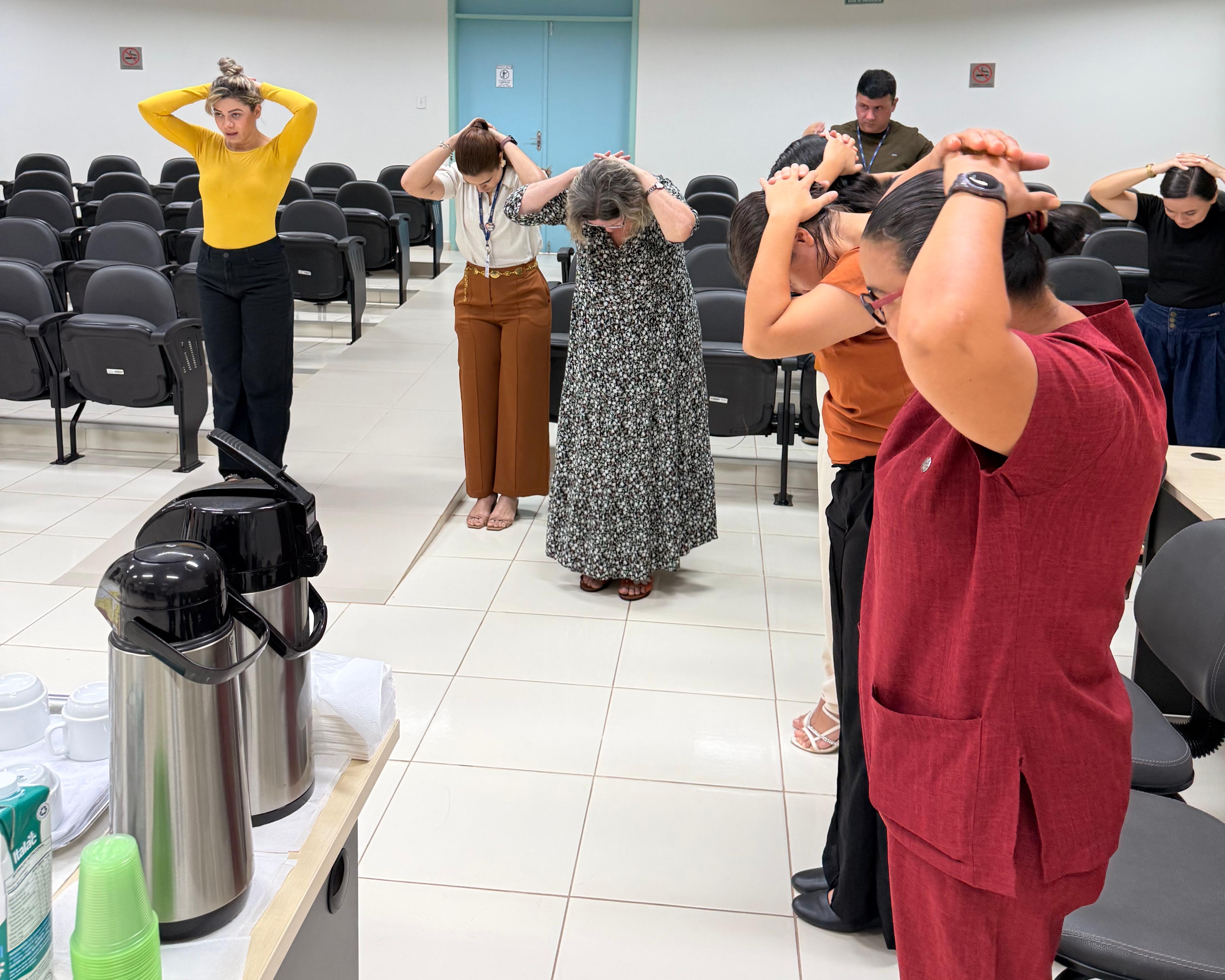 Imagem colorida mostra servidores participando de uma atividade de alongamento e bem-estar durante o Circuito Saúde. O grupo aparece em pé, com as mãos apoiadas sobre a cabeça, acompanhando as orientações em um auditório da unidade judicial. Imagem colorida mostra servidores participando de uma atividade de alongamento e bem-estar durante o Circuito Saúde. O grupo aparece em pé, com as mãos apoiadas sobre a cabeça, acompanhando as orientações em um auditório da unidade judicial.