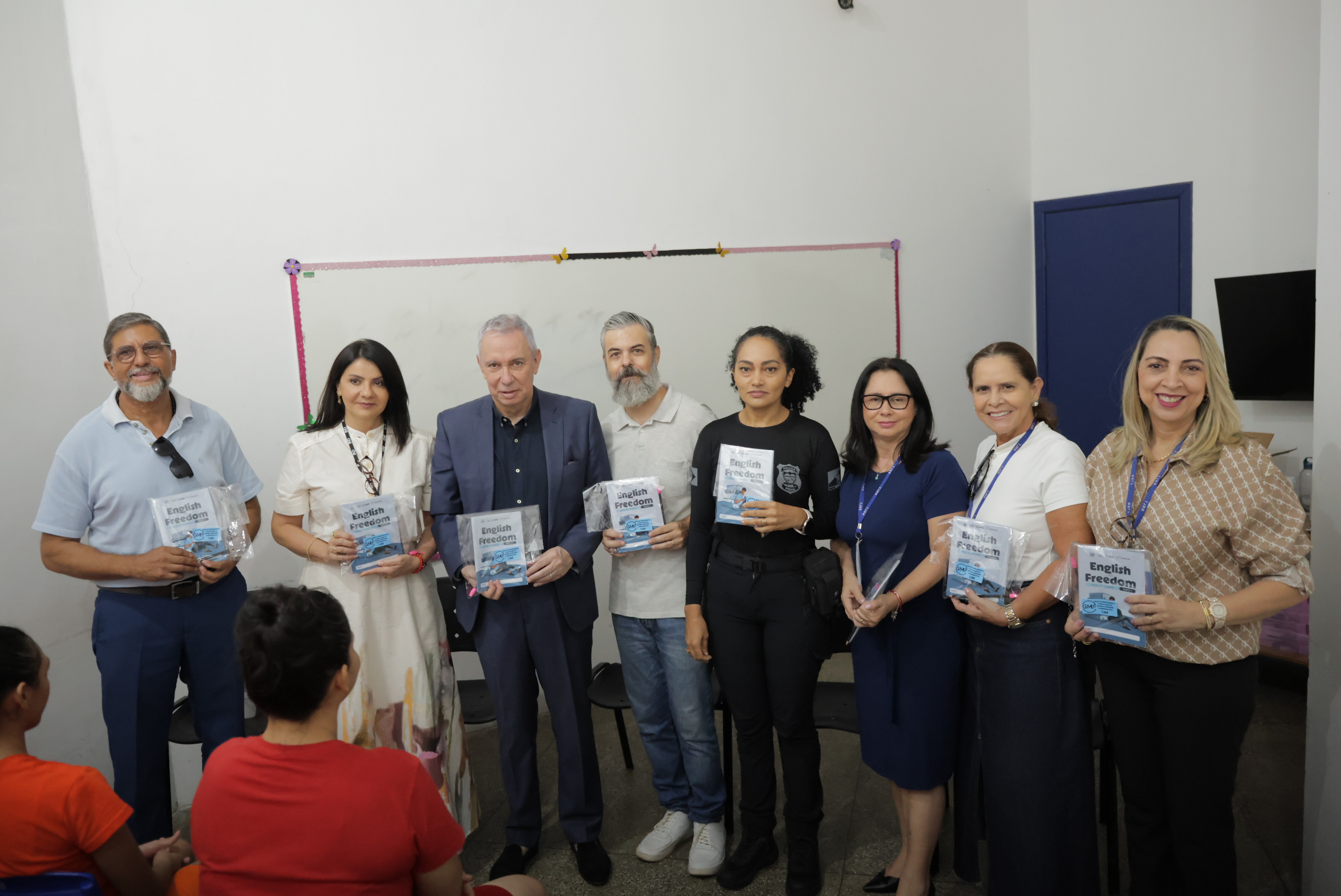 Grupo de 10 pessoas pousando para fotografia e segurando a cartilha de ingles Grupo de 10 pessoas pousando para fotografia