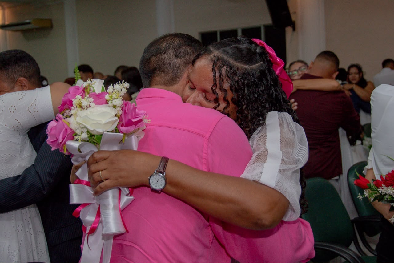 imagem colorida msotra casal de noivos abraçados durante cerimônia de casamento coletivo com participação do TJRR.