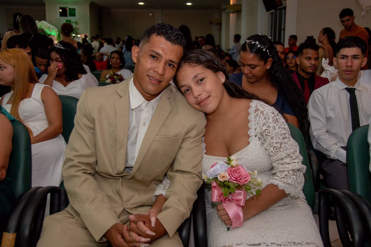 imagem colorida msotra um casal sentado um do lado do outro, durante cerimônia de casamento coletivo com atuação do TJRR.